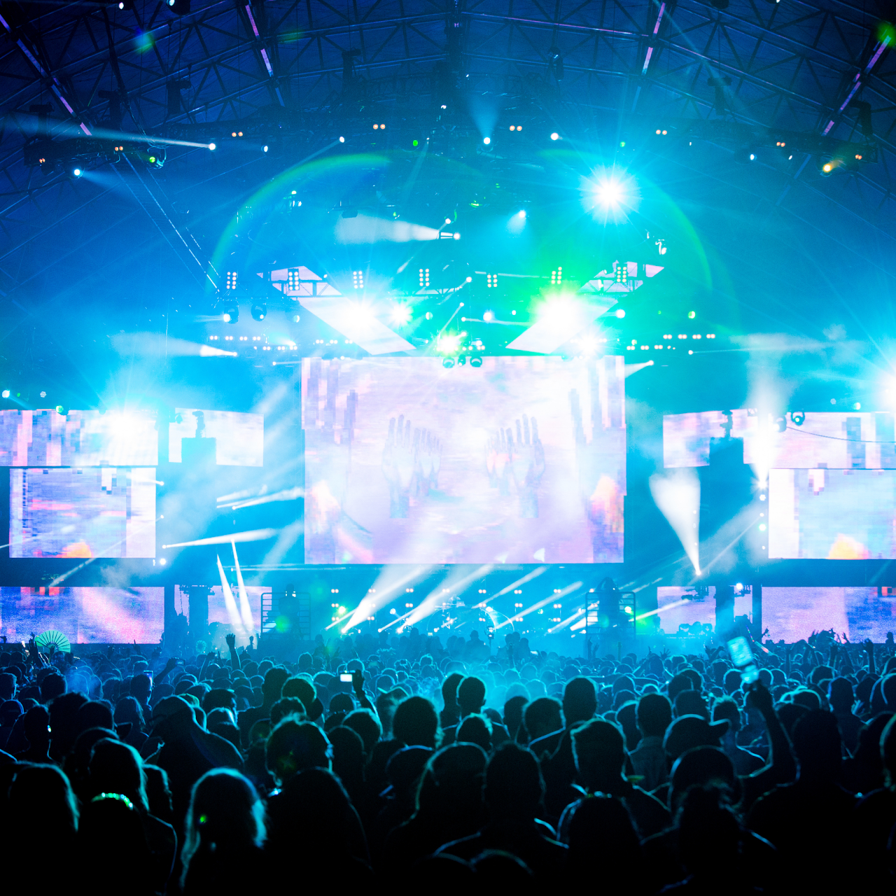 Crowd beneath blue lights at a live music event